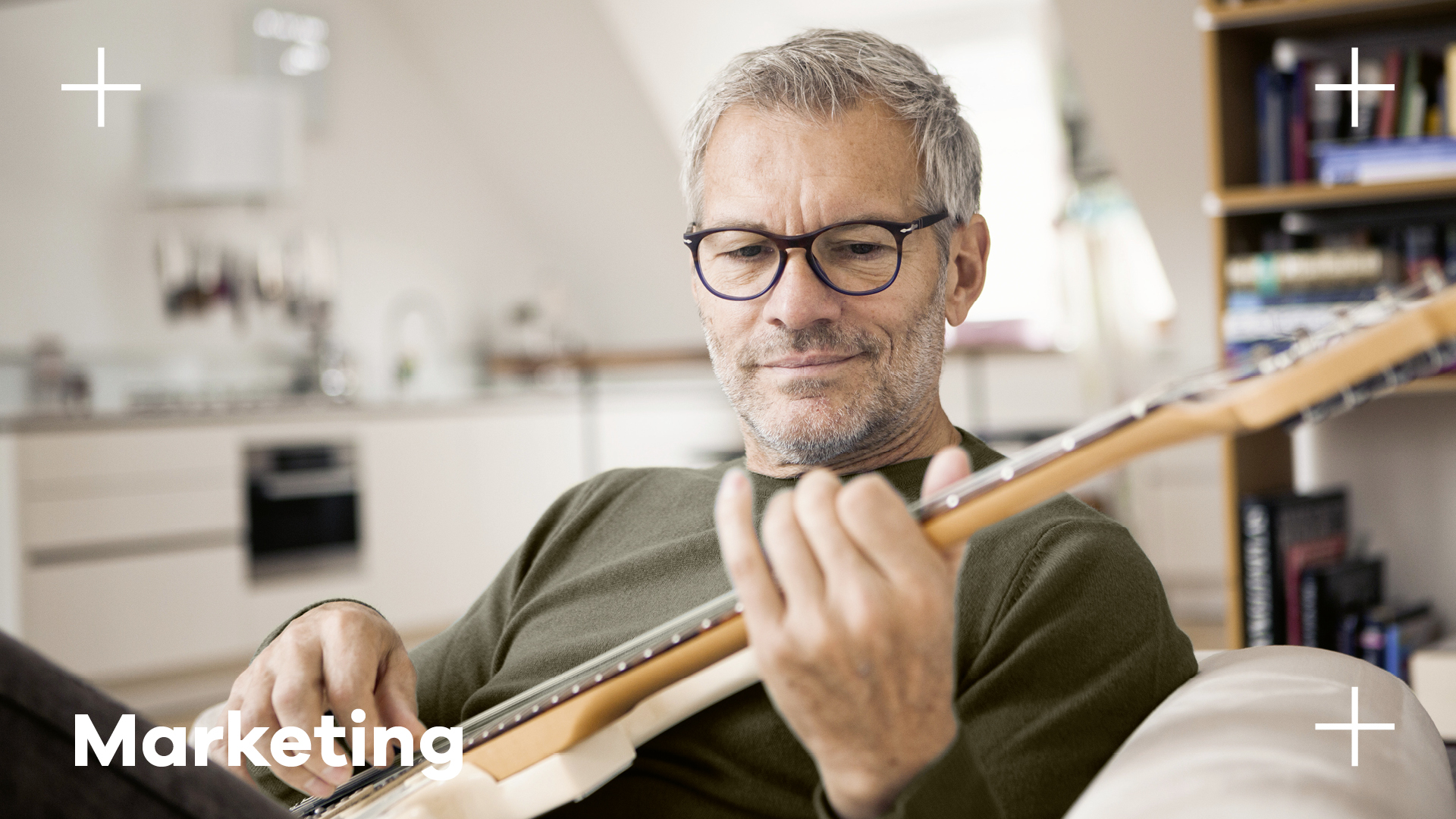 Mann Brillenträger spielt auf dem Sofa sitzend Gitarre Hoya