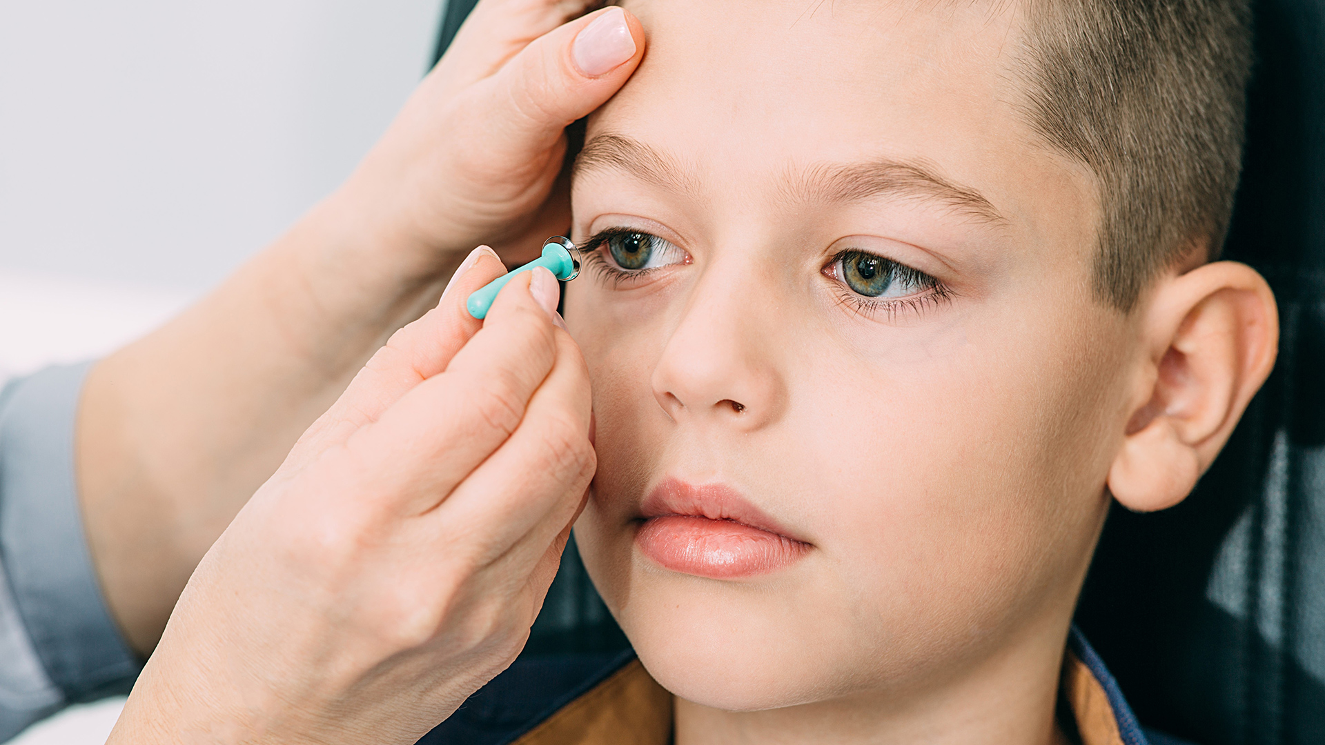 Kind bekommt von Kontaktlinsenanpasser Kontaktlinse eingesetzt
