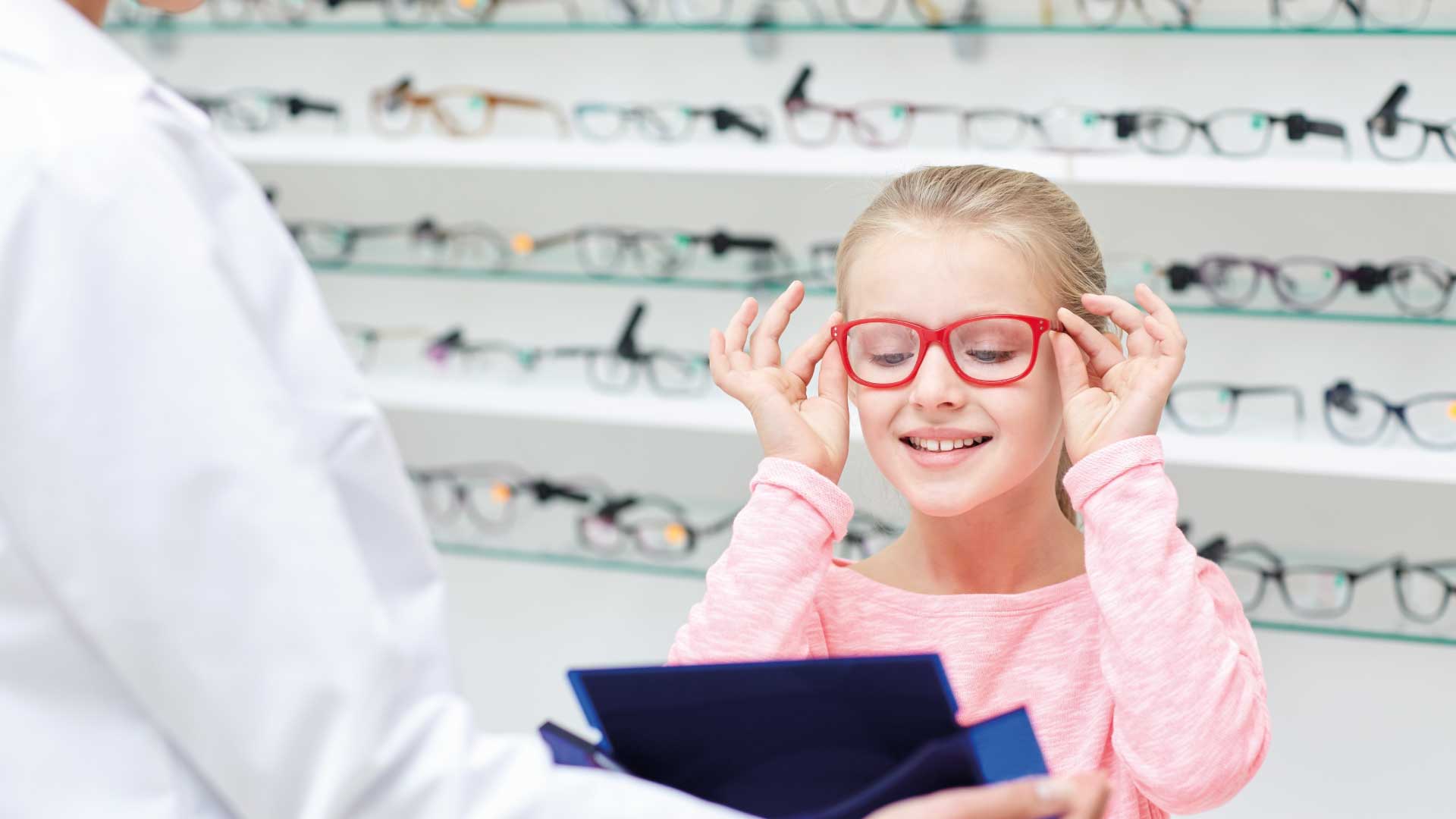 Kind bei der Anprobe einer roten Brille Kinderoptometrie