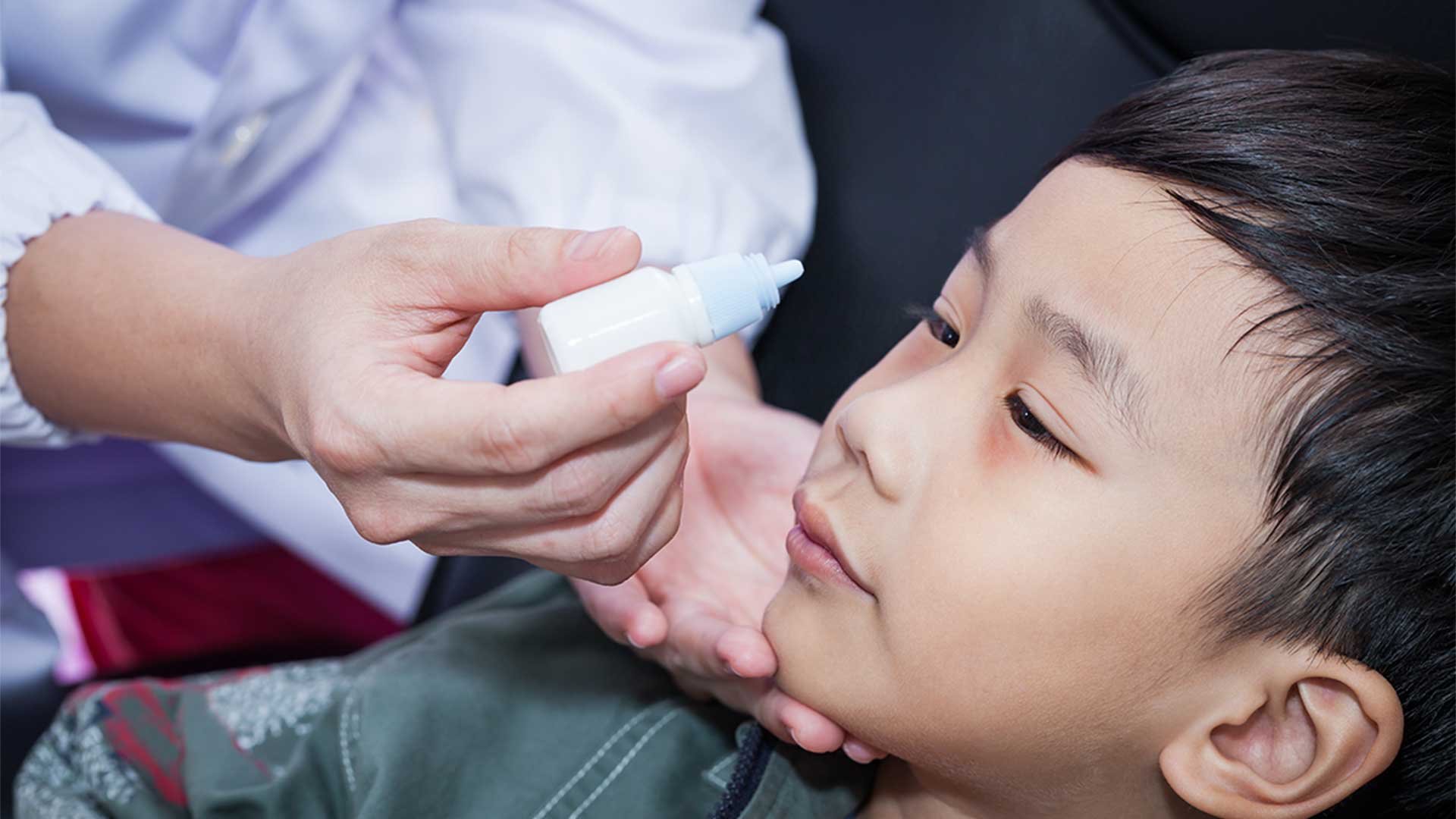 Kind bekommt Augentropfen verabreicht
