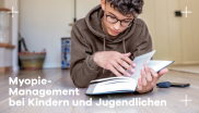 auf dem Boden lesendes Kind Brillenträger Myopie Hoya